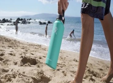 person carrying their hydroflask on a beach